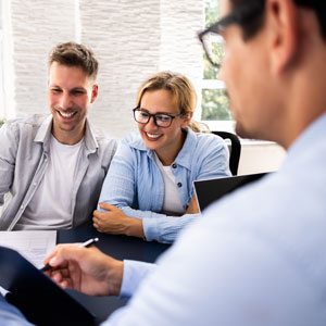 A smiling couple consults with an estate planning lawyer.