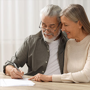 An elderly couple signing a legal document together, representing a serious agreement.