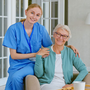 A smiling caregiver and a happy elderly woman in a comfortable setting, representing care and support.